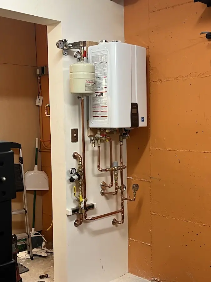 Plumbing technician inspecting water heater connections in Baden